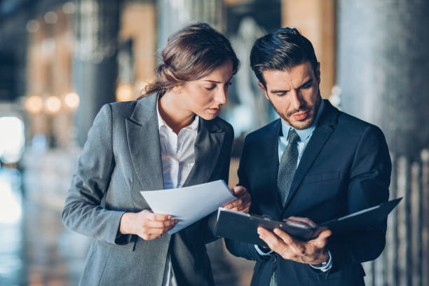 Two business professionals review paperwork together, discussing strategies to minimize costs for an IFZA Free Zone License.