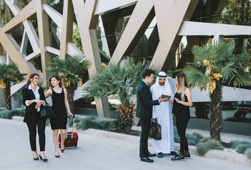 A diverse group of business people collaborate outside a modern office building in IFZA Free Zone.